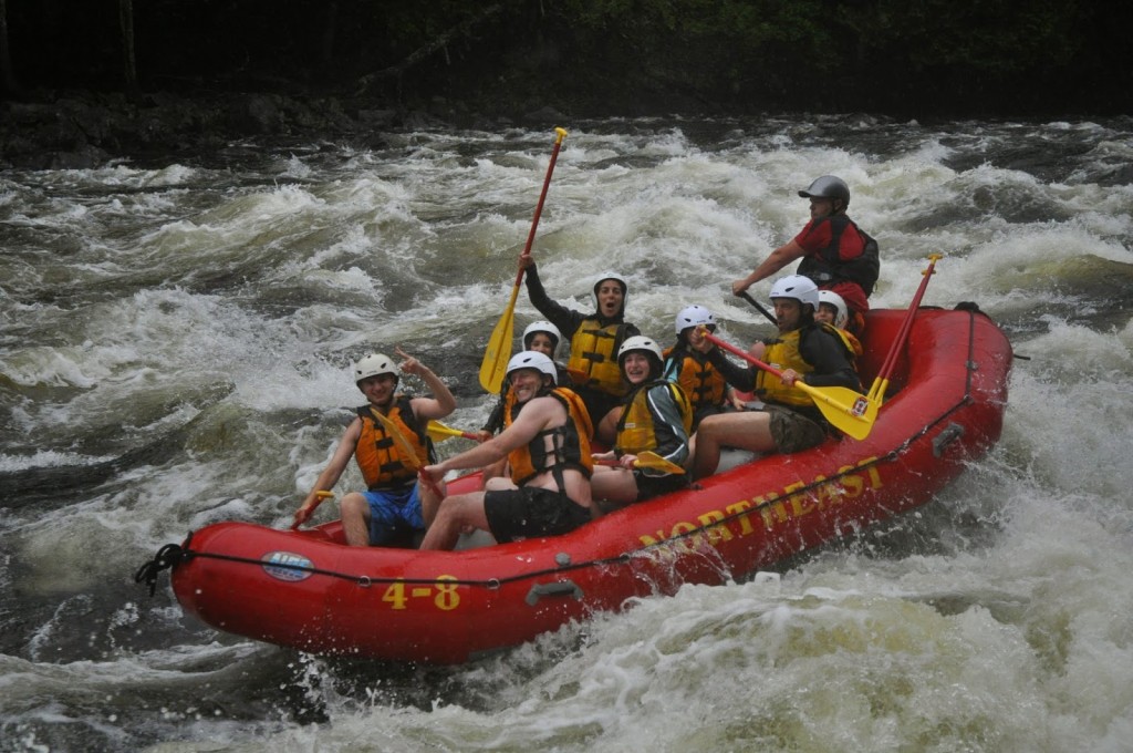 Family having fun white water rafting in a red raft on the Kennebec River in Maine
