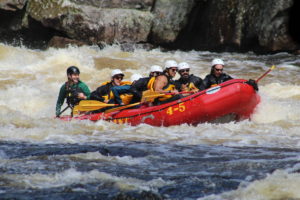 Guests in red raft guided by Northeast Whitewater guide on the Penobscot River