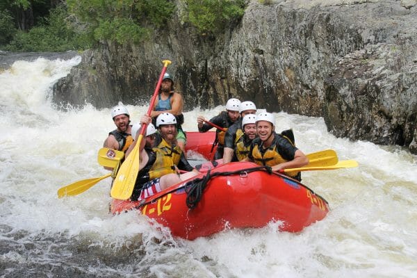 Closeup of People smiling while Whitewater Rafting in a red raft in Maine