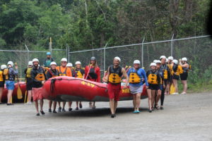 Family of 8 carrying red raft together