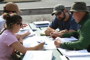 Four People Sitting on a Bench Going Over Paperwork