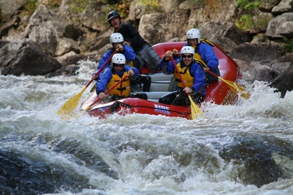 Group of four people on a red raft on the Penobscot River in Maine whitewater rafting