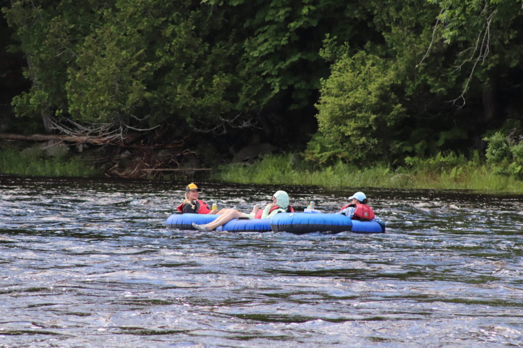 Three people sitting in blue tubes floating down the Kennebec River