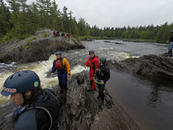 People Walking on Wet Rocks on a River