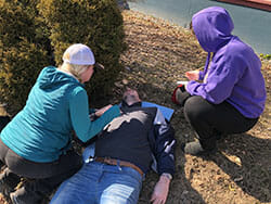 Two People Helping an Injured Person on the Ground